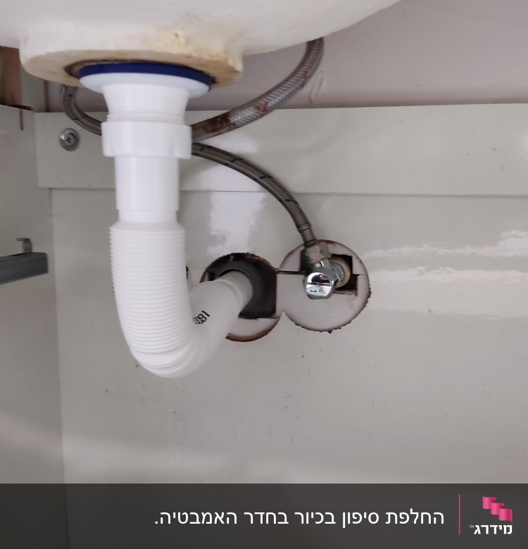 צינור פלסטיק לבן מתחת לכיור עם חיבורי מתכת